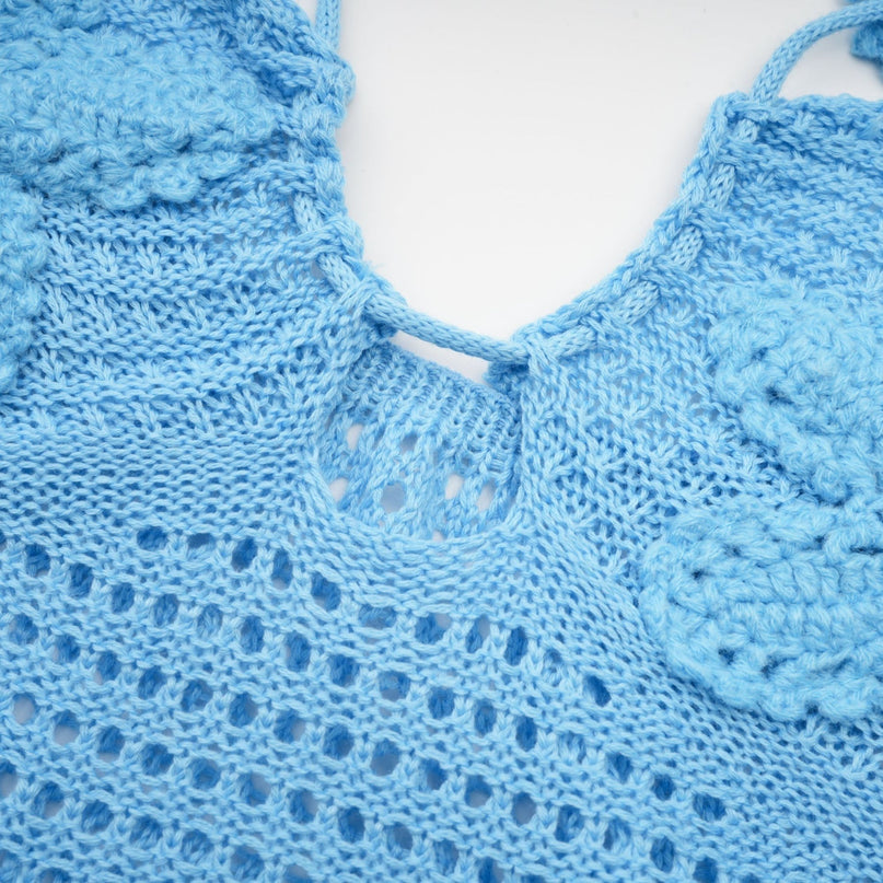 A long white crochet maxi dress with colorful faux flower embellishments scattered across the bodice and skirt