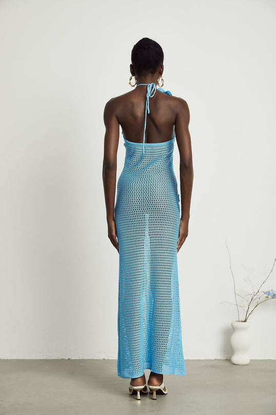 A long white crochet maxi dress with colorful faux flower embellishments scattered throughout the design