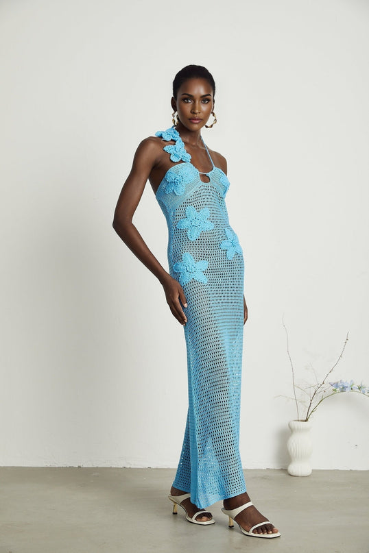 A long white crochet maxi dress with colorful faux flower embellishments scattered throughout the design