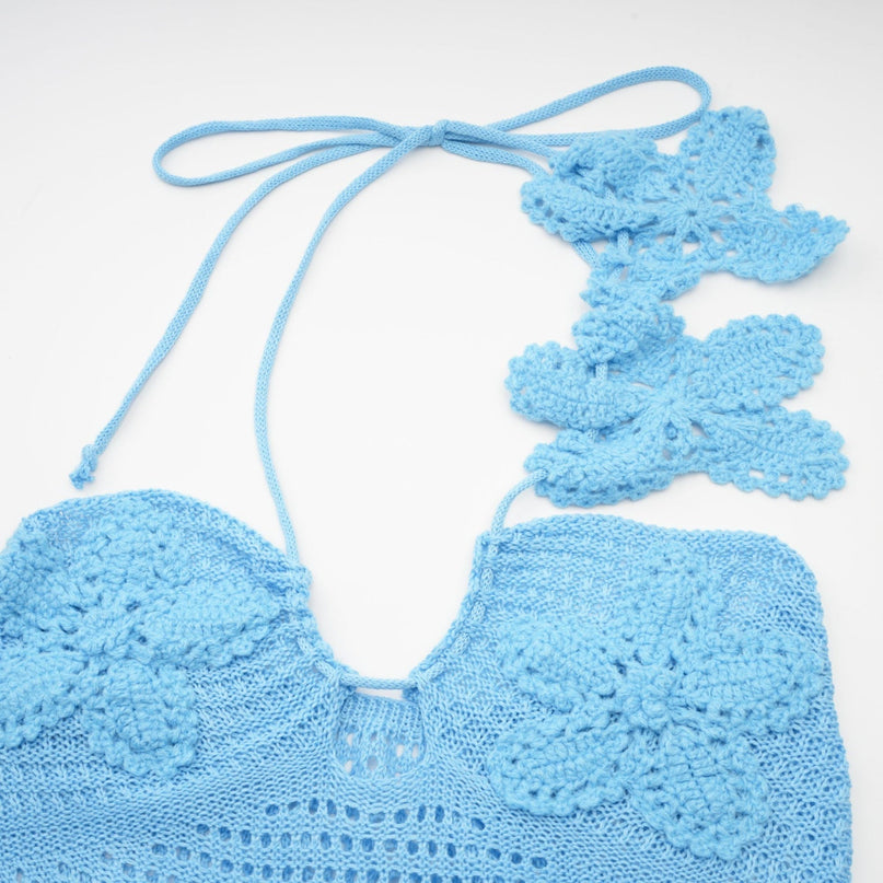 A long white crochet maxi dress with colorful faux flower embellishments scattered throughout the design