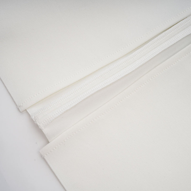 A long white fitted maxi dress with floral applique details featuring a bandage style design and named Olivia