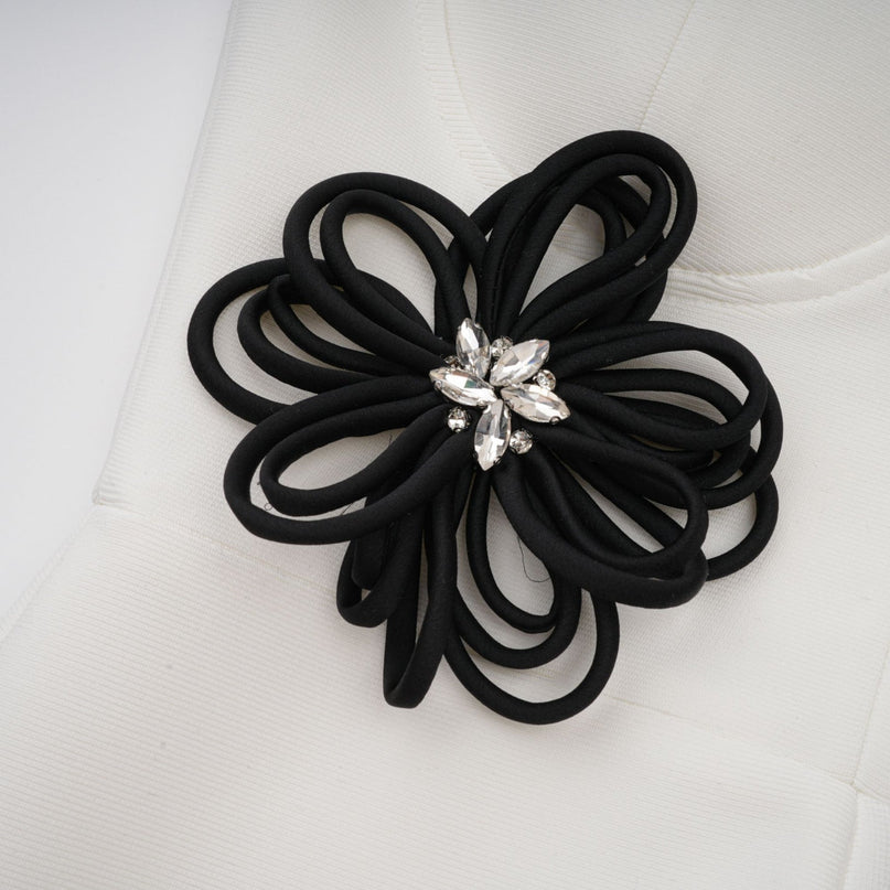 A long white formfitting dress with floral applique details and a bandage style design