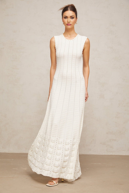 A long white knit dress with a pointelle pattern and faux pearl embellishments