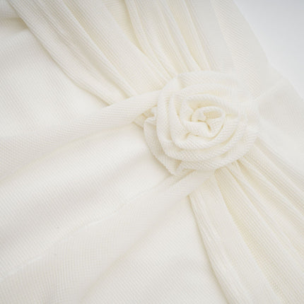 A long white knit maxi dress with glittery floral applique designs adorning the fabric named Wanda