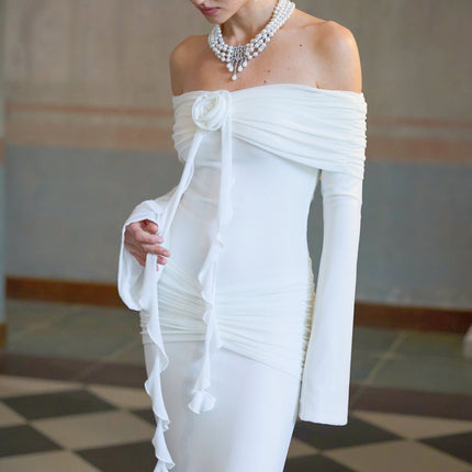 A long white knit maxi dress with glittery floral appliques adorning the fabric named Wanda