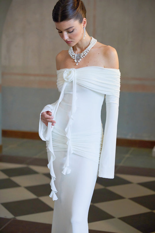 A long white knit maxi dress with glittery floral appliques adorning the fabric named Wanda