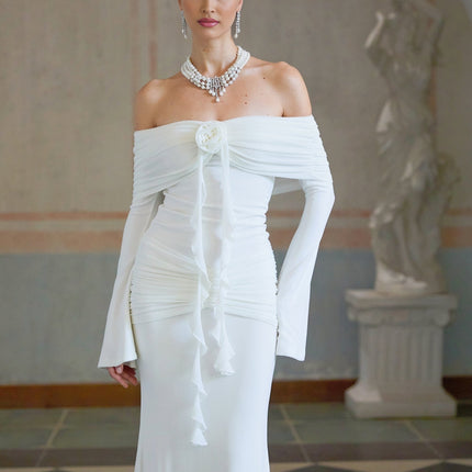 A long white knit maxi dress with glittery floral appliques decorating the fabric