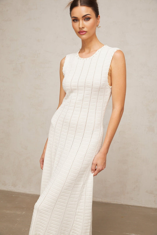 A long white knit maxi dress with pointelle detailing and faux pearl embellishments