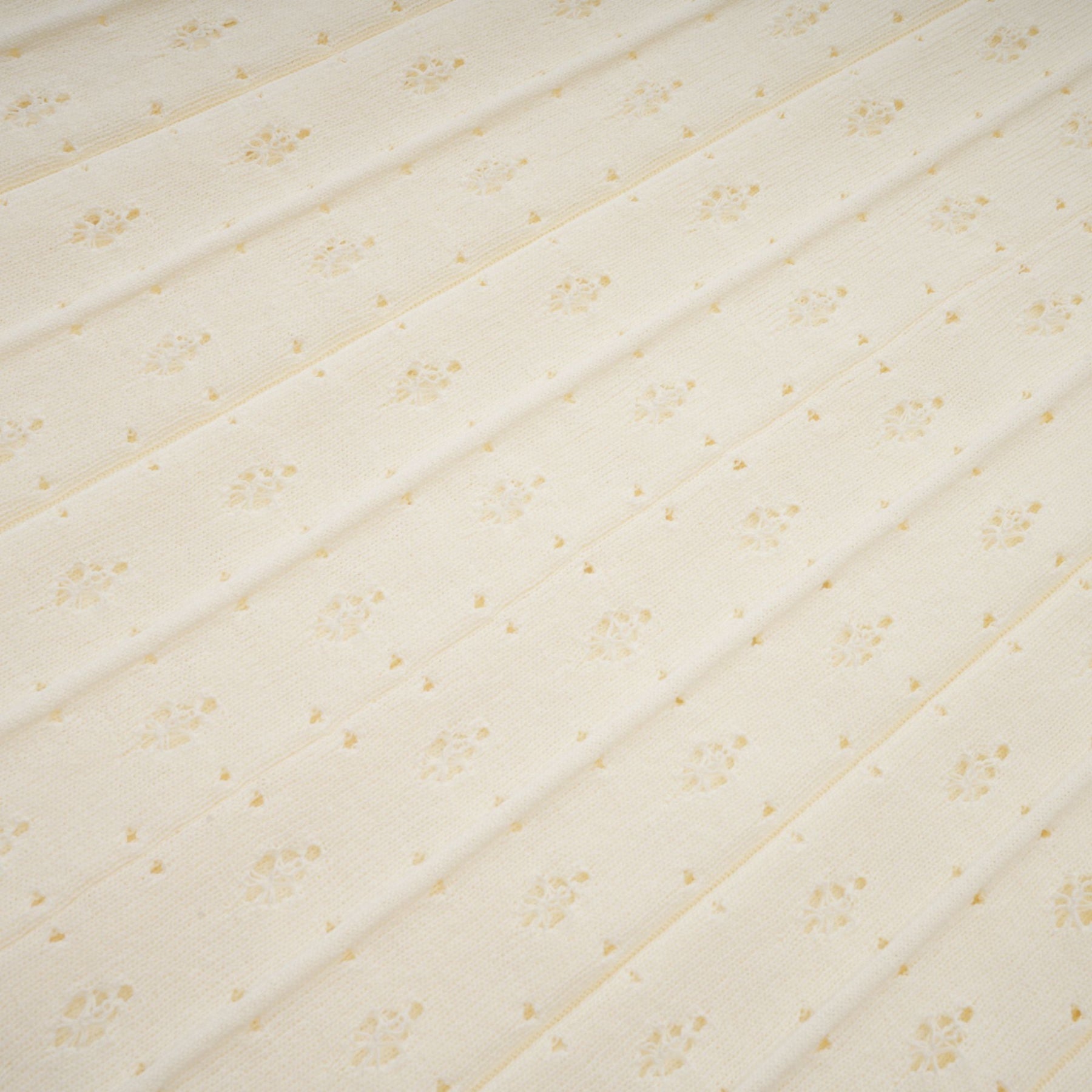 A long white knitted maxi dress with faux pearl embellishments throughout the fabric