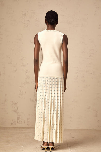 A long white knitted maxi dress with faux pearl embellishments throughout the fabric