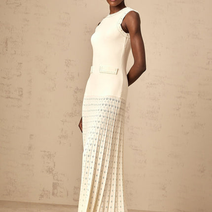 A long white knitted maxi dress with faux pearl embellishments throughout the fabric