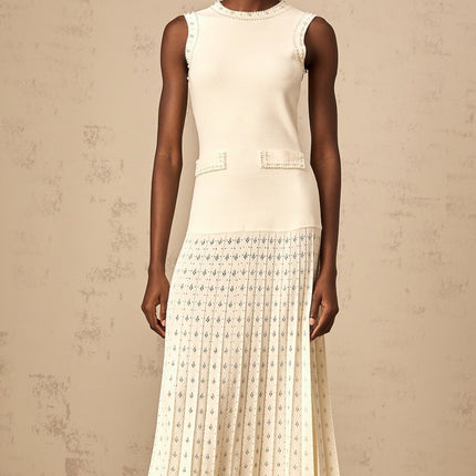 A long white knitted maxi dress with faux pearl embellishments throughout the fabric