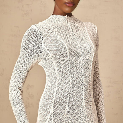 A long white lace maxi dress with a wavy pattern design featuring intricate details and a flowing silhouette