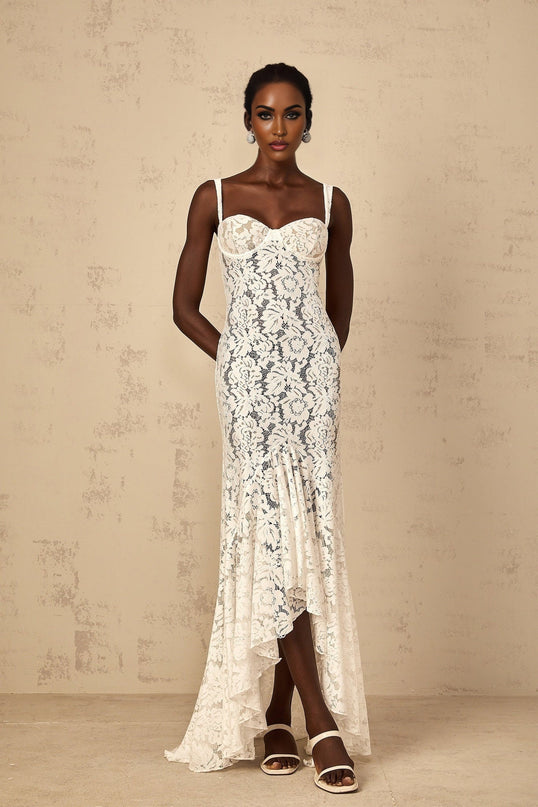 A long white maxi dress with a floral lace pattern and bustier top featuring thin straps and a fitted bodice