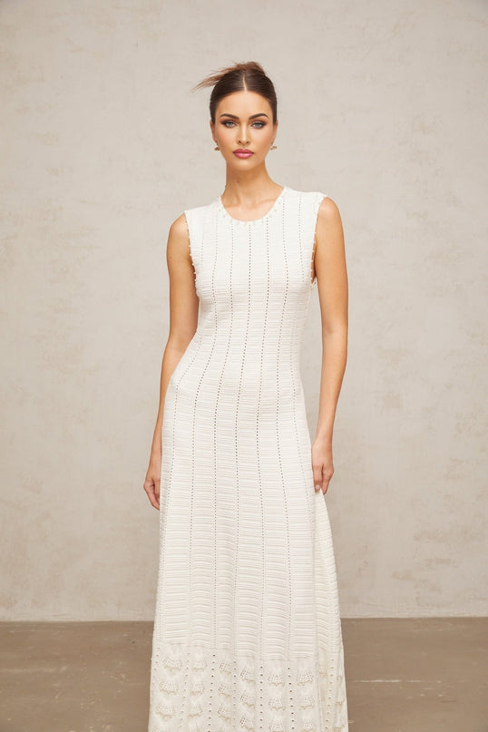 A long white maxi dress with a pointelle knit pattern adorned with faux pearl embellishments throughout the fabric