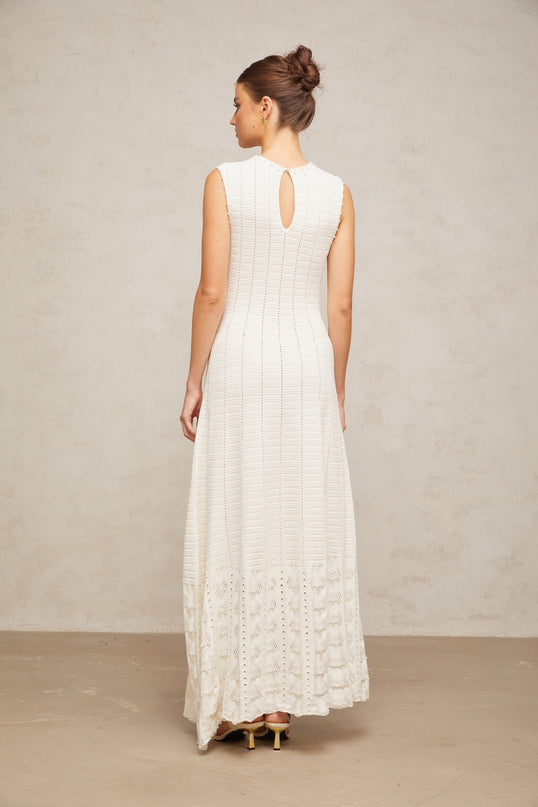 A long white maxi dress with a pointelle knit pattern and faux pearl embellishments