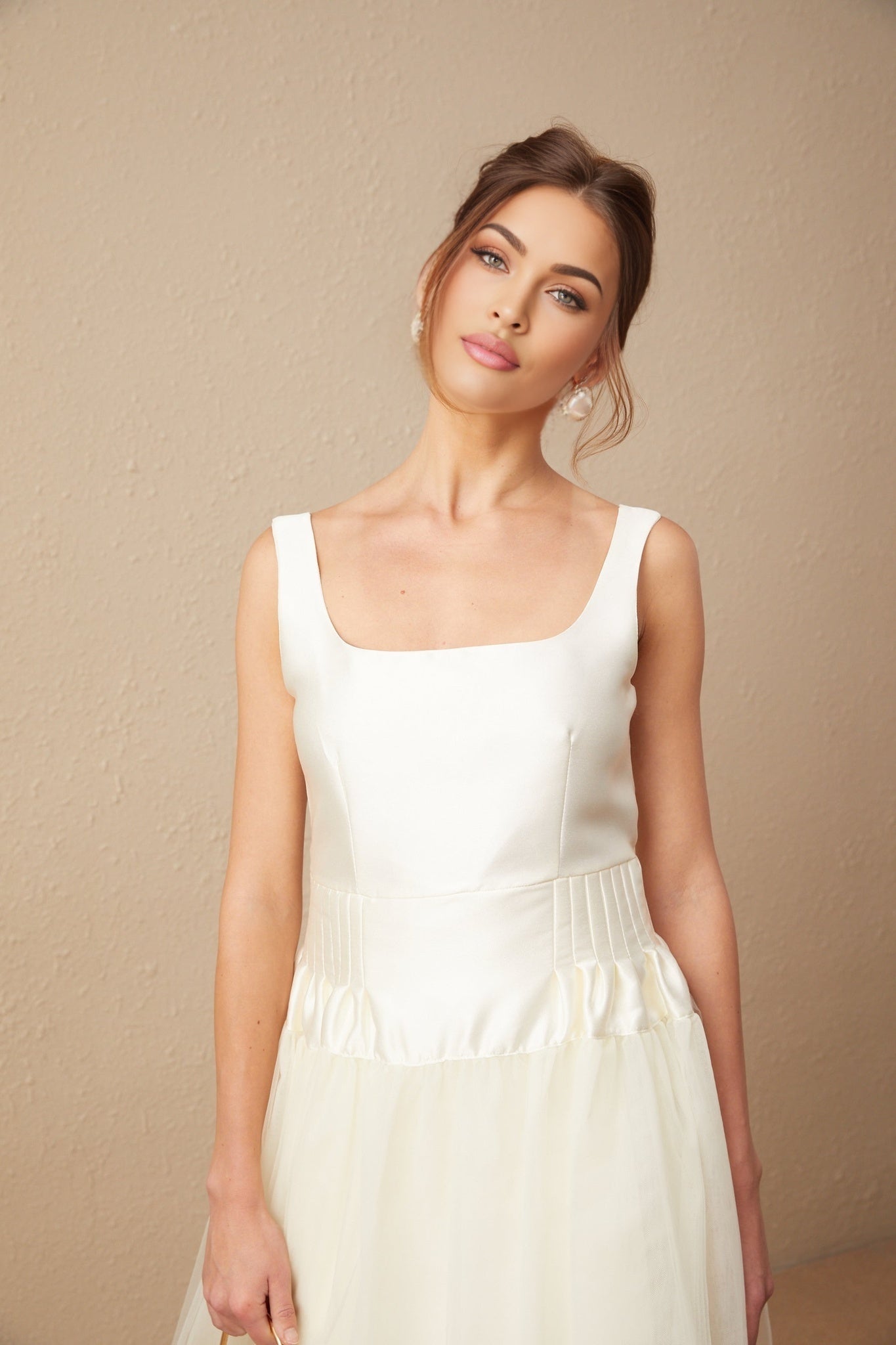 A long white maxi dress with a satin bodice and flowing tulle skirt featuring sheer panelled details