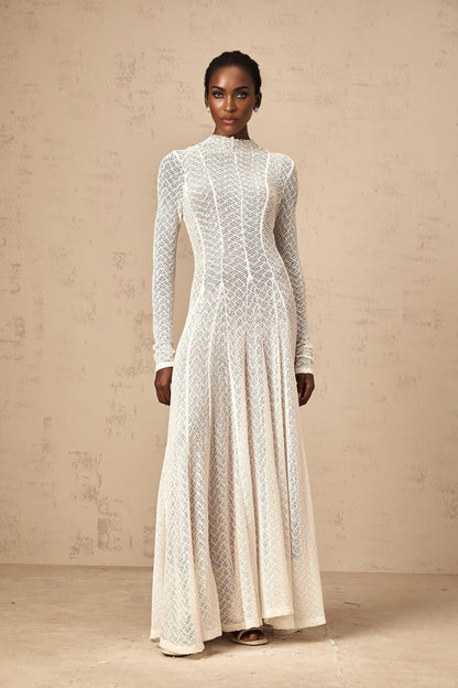 A long white maxi dress with a wavy lace pattern covering the entire garment featuring a feminine and elegant design