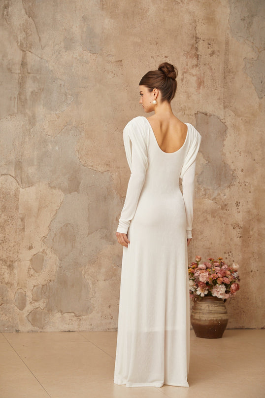 A long white maxi dress with draped and shirred details featuring a flowing silhouette and elegant design