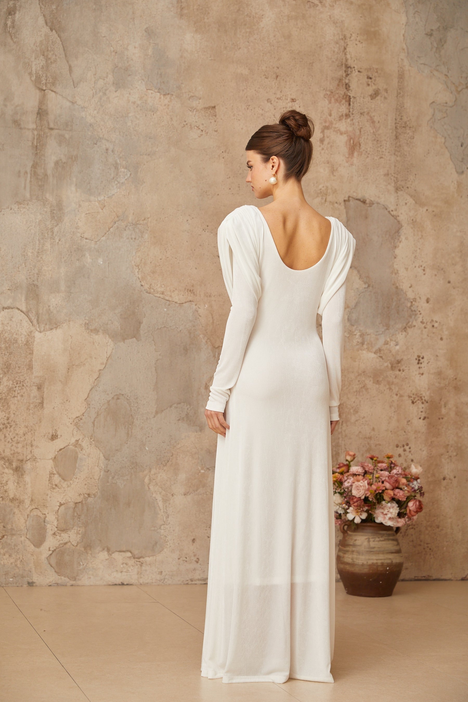 A long white maxi dress with draped and shirred details featuring a flowing silhouette and elegant design