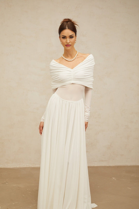 A long white maxi dress with draped details and ruching featuring a fitted silhouette and flowing skirt