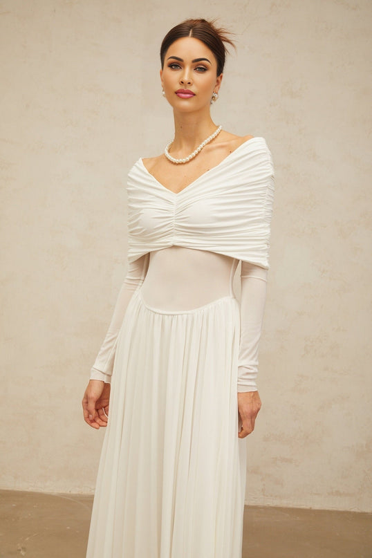 A long white maxi dress with draped details and ruching featuring a fitted silhouette and flowing skirt