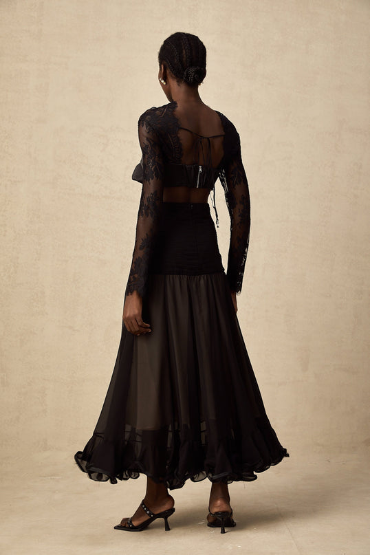 A long white maxi dress with floral lace panels and sheer details featuring a high neckline and long sleeves