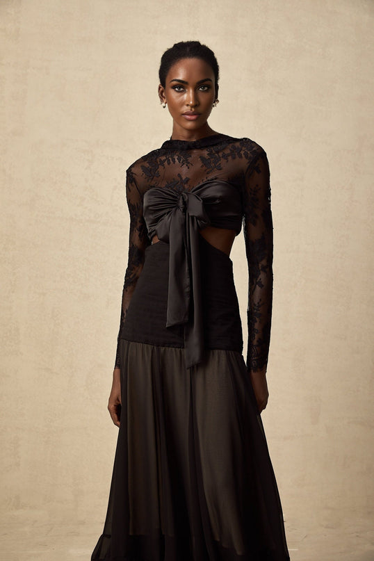 A long white maxi dress with floral lace panels and sheer sections flowing elegantly to the floor