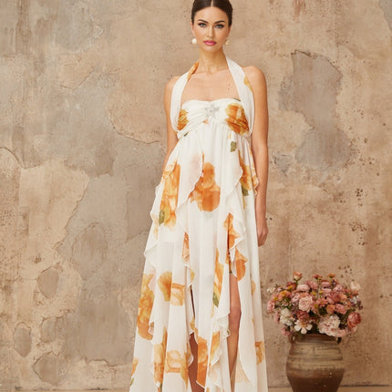 A long white maxi dress with floral print and ruffled tulle details modeled on a woman against a plain background