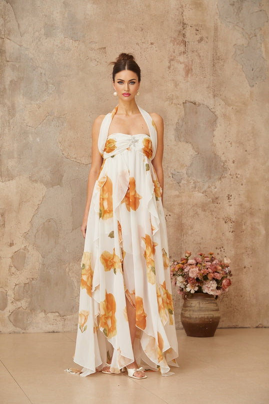 A long white maxi dress with floral print pattern and ruffled tulle details worn by a model against a plain background