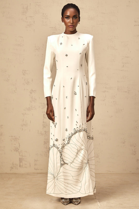A long white maxi dress with lotus flower embellishments and a flowy silhouette