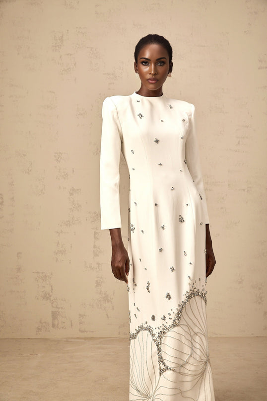 A long white maxi dress with lotus flower embellishments and a flowy silhouette