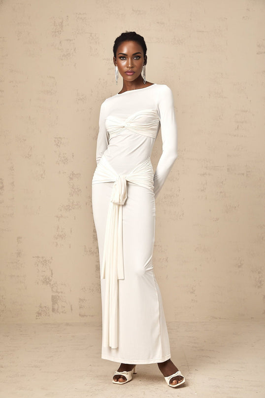 A long white maxi dress with ruched detailing and a ribbon twist accent at the waist named Elena