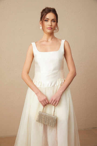 A long white maxi dress with satin and tulle panels featuring a fitted bodice and flowing skirt