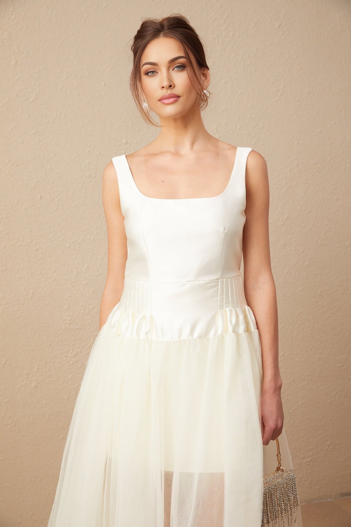 A long white maxi dress with satin bodice and flowy tulle skirt featuring side panels
