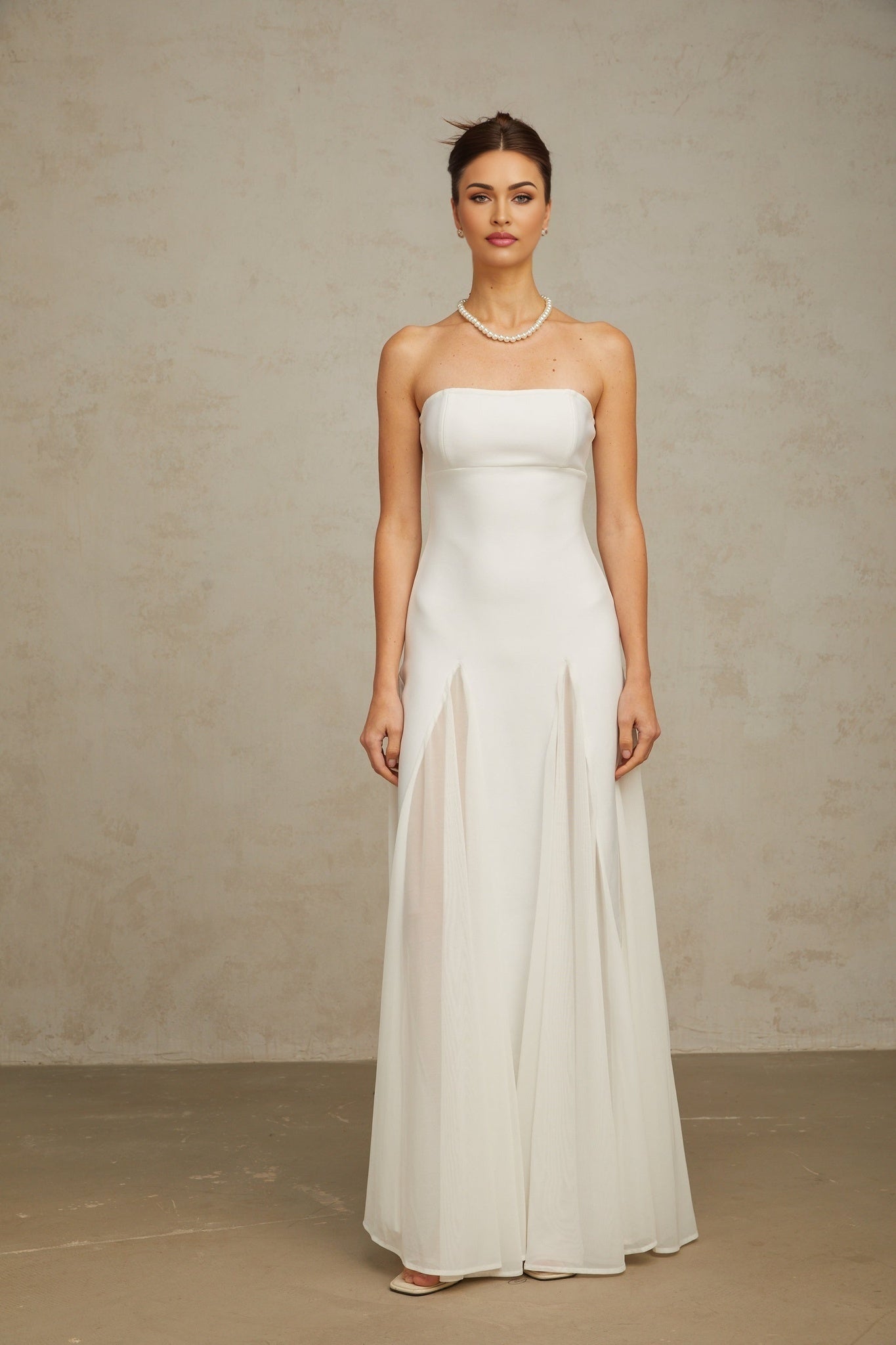 A long white maxi dress with tulle panels featuring a sleeveless design and flowing silhouette
