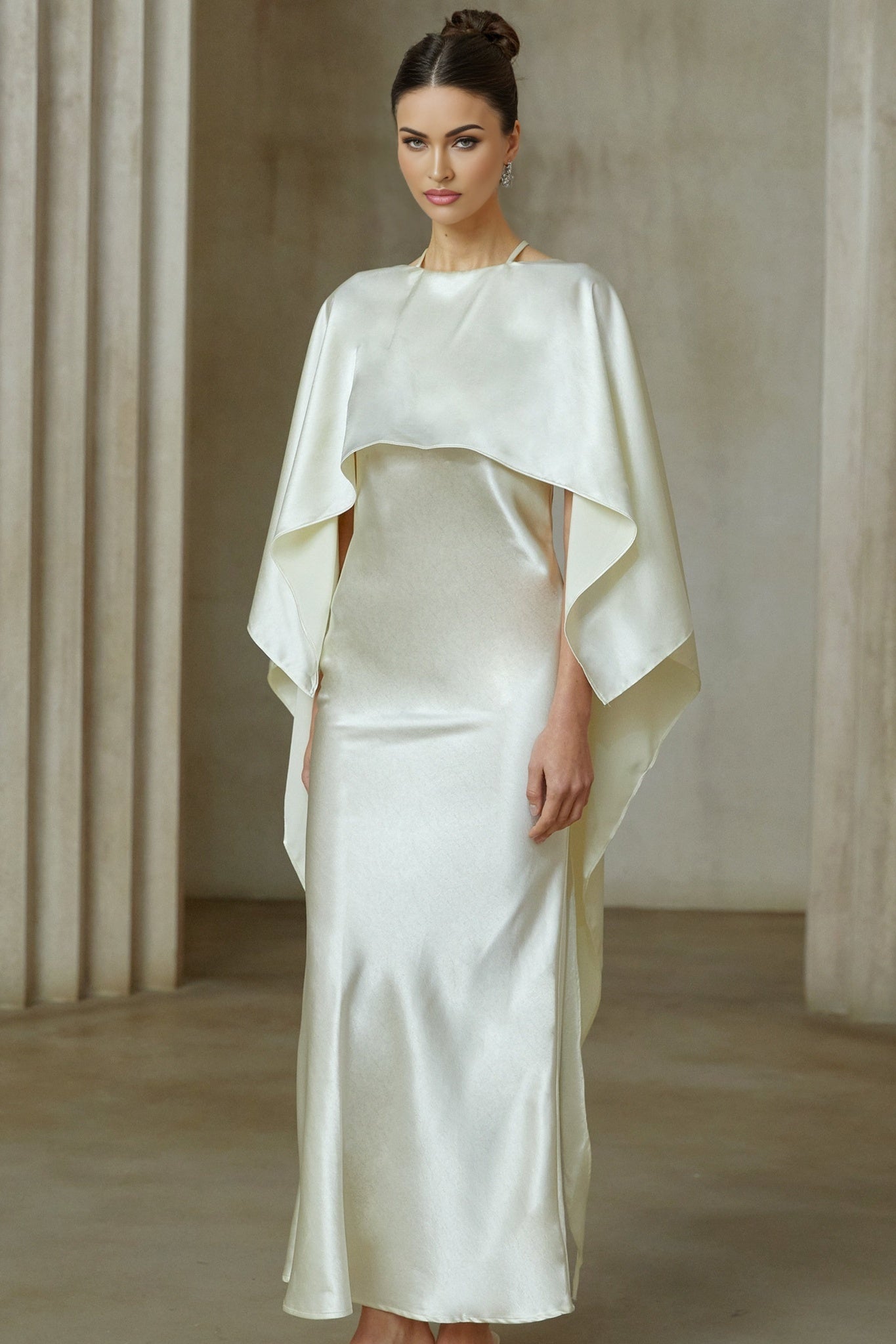 A long white satin maxi dress with a shawl panel draped over the shoulders creating an elegant flowing silhouette