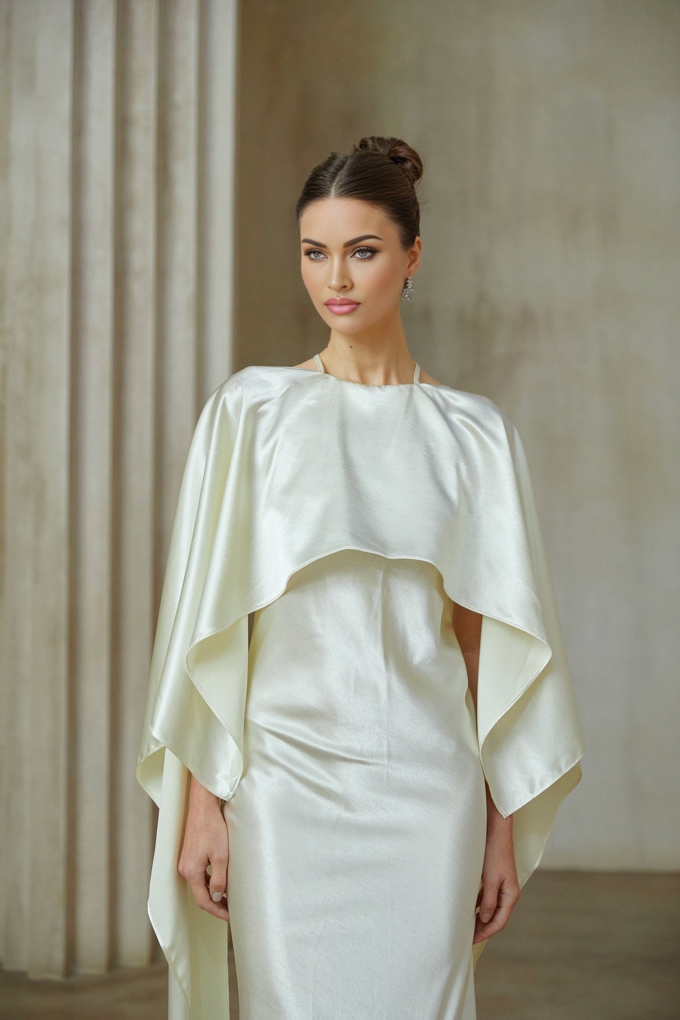 A long white satin maxi dress with a shawl panel flowing over the shoulders and bodice