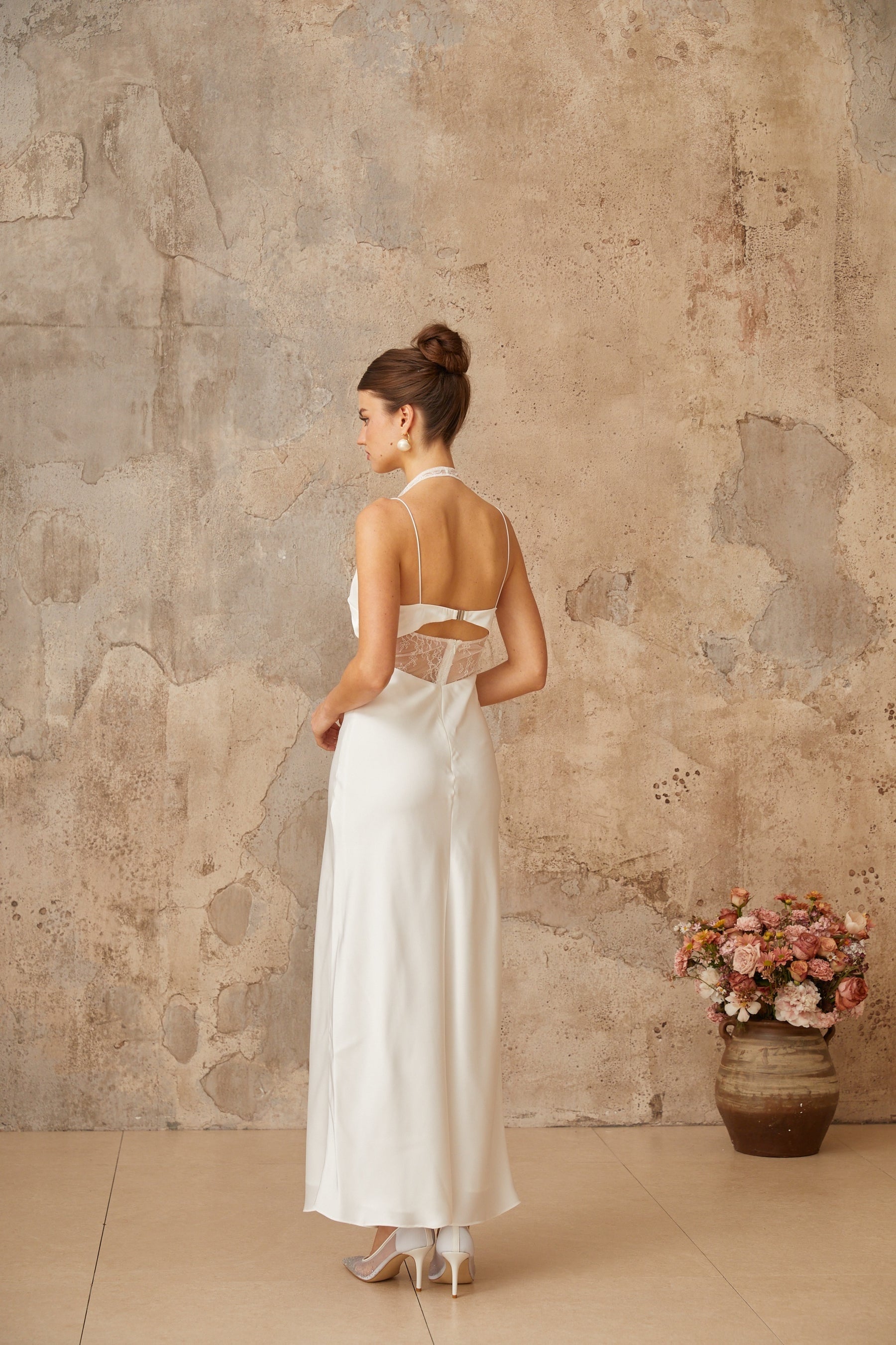 A long white satin maxi dress with lace panel details and a flowing silhouette