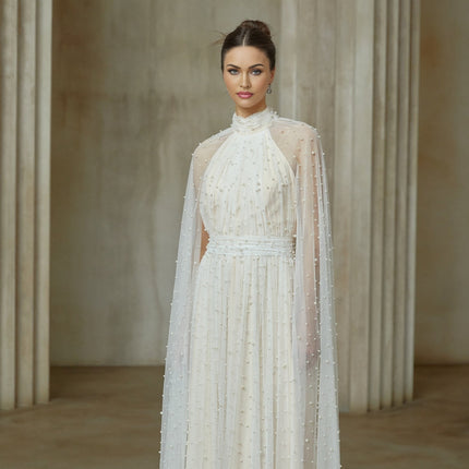 A long white tulle maxi dress with cape design and embellishments featuring a flowy silhouette and delicate details