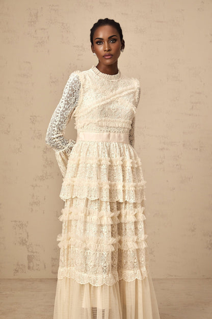 A long white tulle maxi dress with lace panels and ruffled details featuring a romantic and ethereal design in neutral tones