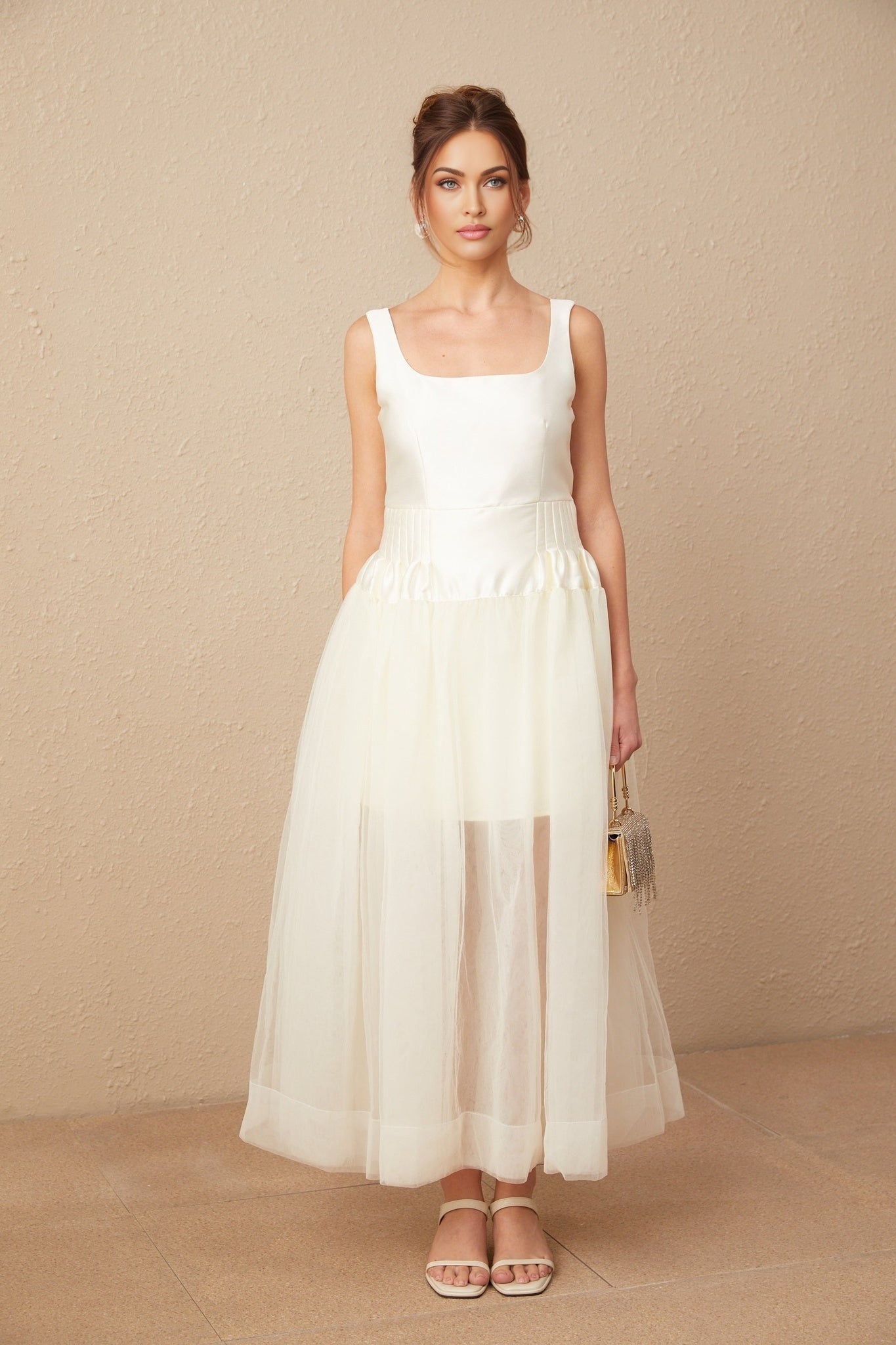 A long white wedding dress with a satin bodice and flowing tulle skirt featuring panels for a layered look