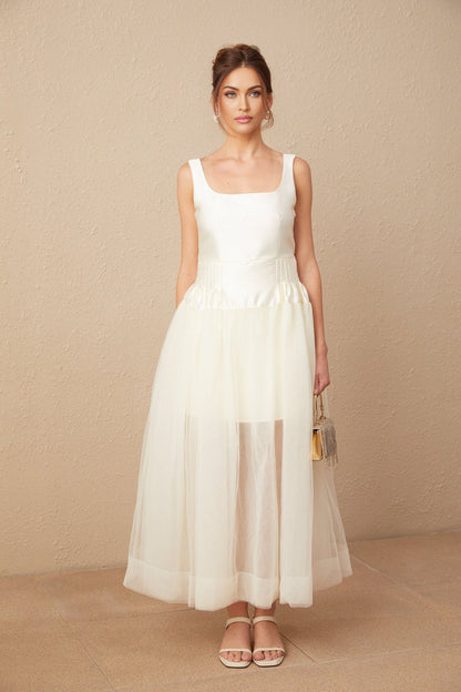 A long white wedding dress with a satin bodice and flowing tulle skirt featuring panels for a layered look