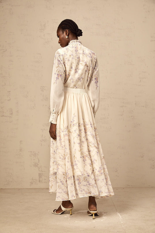 A matching set consisting of a frilled shirt and skirt with a wisteria print pattern in a Siena style The shirt features ruffled details while the skirt complements the top Both pieces are adorned with a delicate floral design in shades of purple