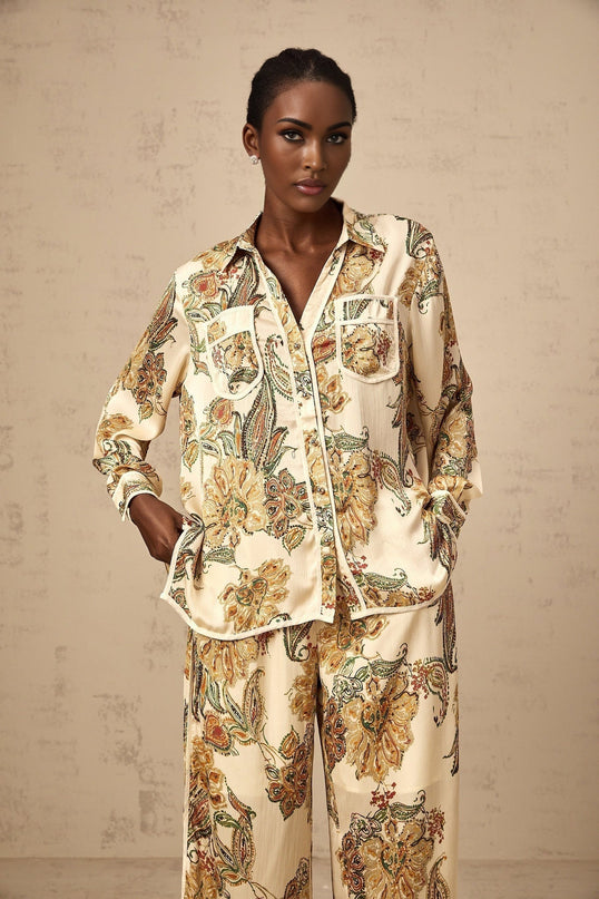 A matching set consisting of a shirt and trousers in neutral colors with a floral print pattern featuring the Agnès design