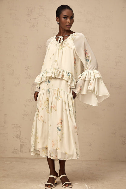 A matching set featuring a floral print blouse with ruffles and a coordinating dress in the same pattern and colors