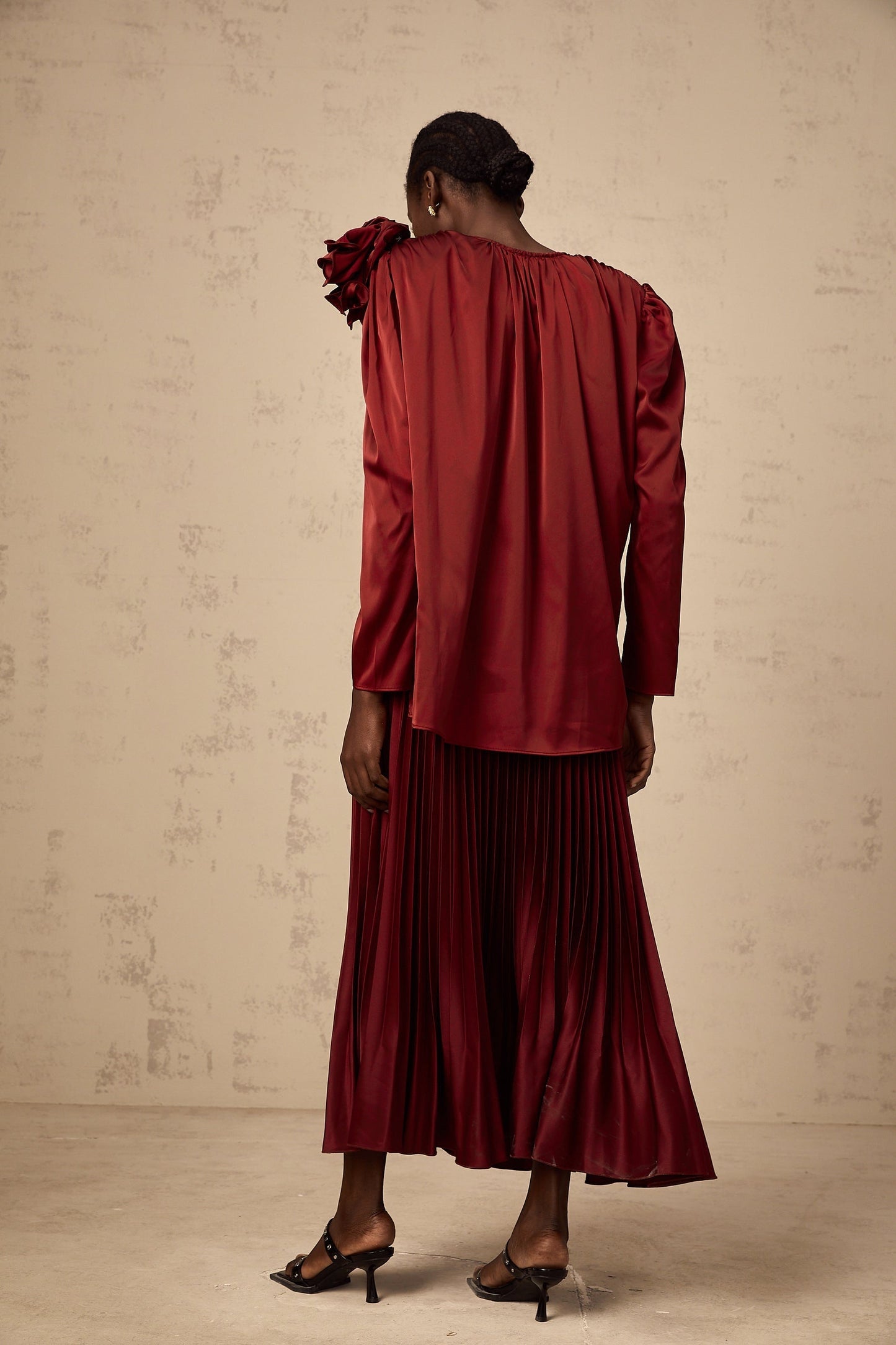 A matching set featuring a satin blouse and skirt with floral applique details The blouse and skirt are coordinated in style and color showcasing delicate flower embellishments on a smooth satin fabric