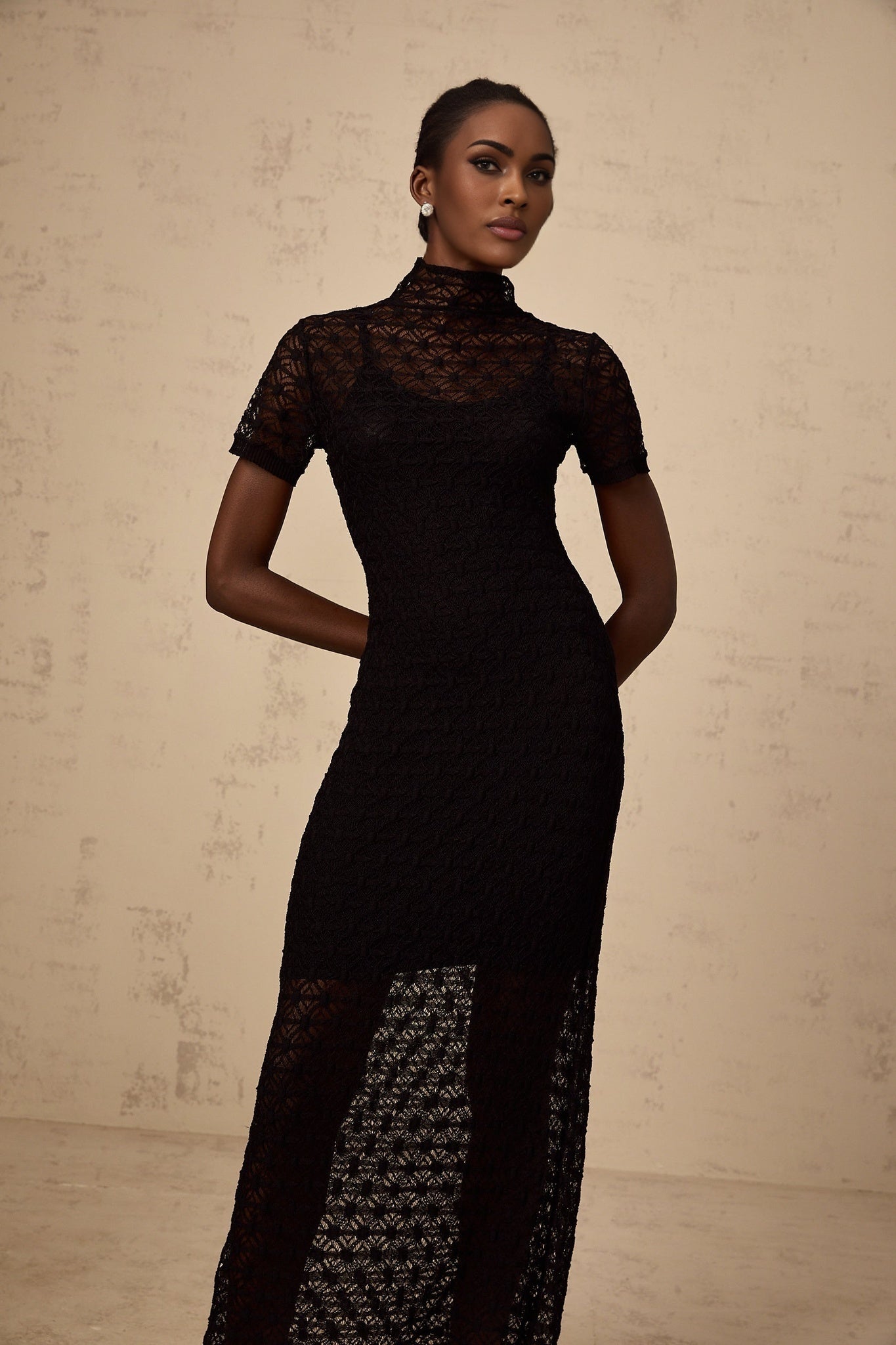 A model wearing a black semisheer knit midi dress with a fitted silhouette and long sleeves