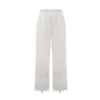 A model wearing a matching set consisting of a cropped top and trousers in white The top features lace trim and cutout details The trousers are high waisted and flared The set has a romantic and feminine style