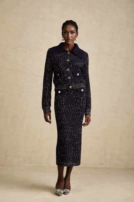 A navy blue crochet knit jacket and matching skirt set called Claudine The jacket and skirt feature an intricate crochet pattern The ensemble is a coordinated outfit suitable for formal or evening wear
